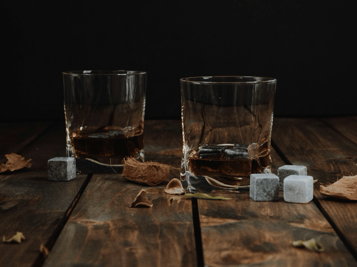 Two whiskey glasses on a dark wooden table, illustrating a Father's Day drink gift for a dad with an established taste